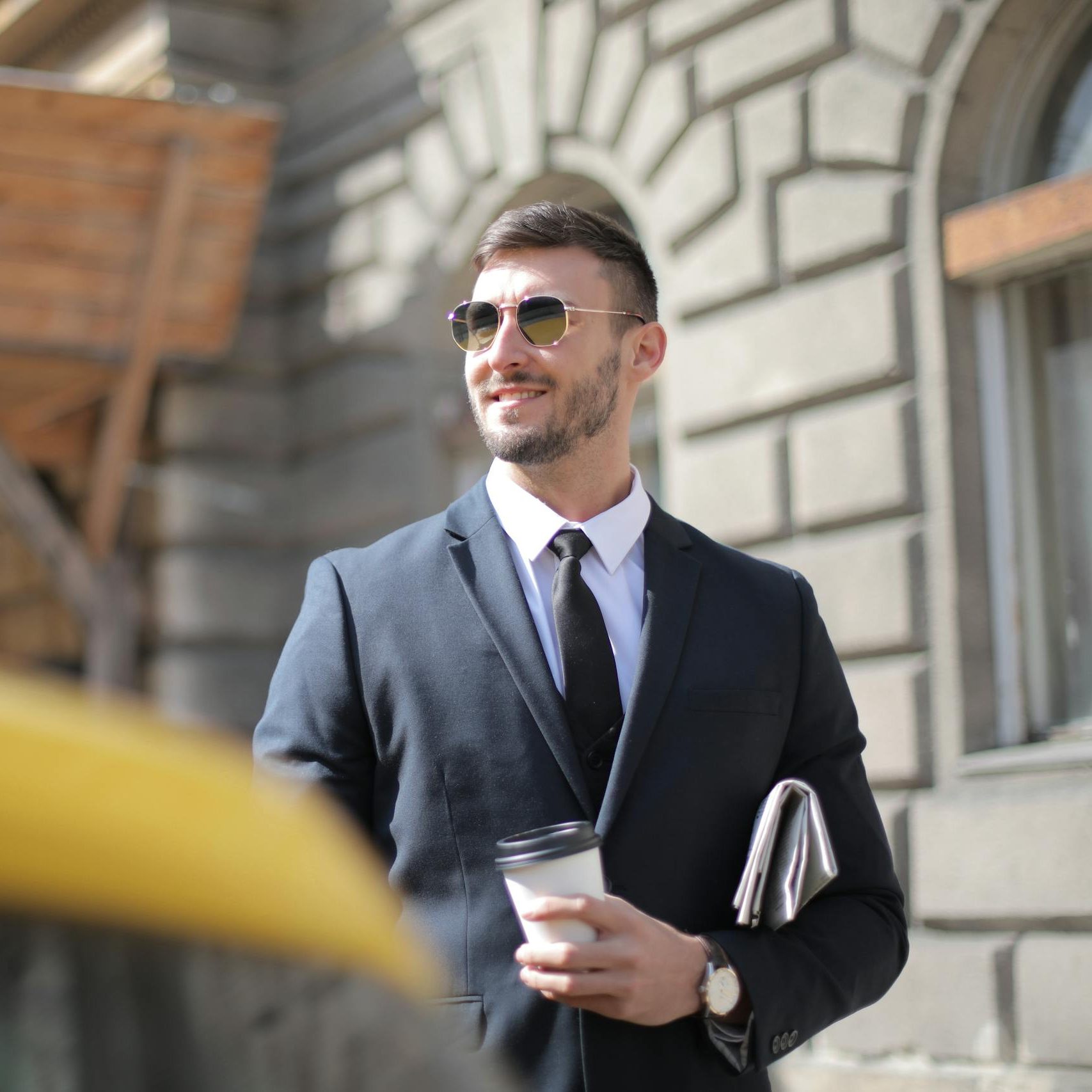 Man In Black Suit Holding A Cup Of Coffee